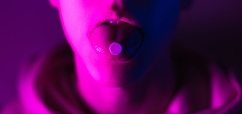 Young man taking a hallucinogen pill